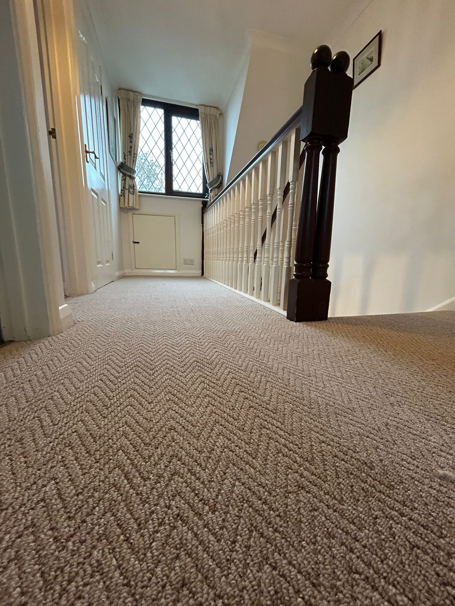 Carpet fitter in uniform installing a new carpet in a Hastings home with the furniture moved aside.